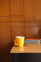  yellow color mug mockup with with notebooks on table 