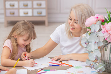 30 years old caucasian mother helping her cute litte daughters draw together