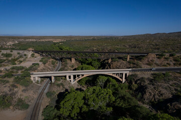 Aerial of a train trestle and an arched bridge over a small canyon