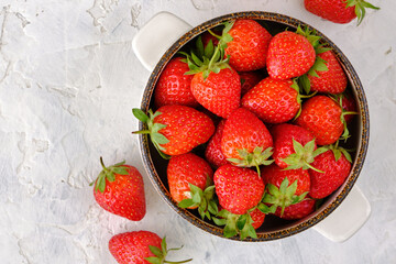 Juicy, bright and sweet strawberries in a bowl on a white concrete table