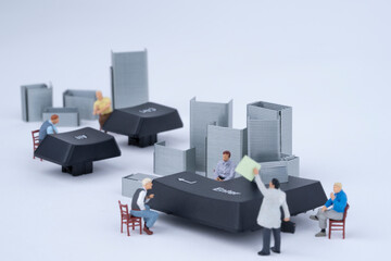 miniature man who is tired of work is sitting in a chair between a chatting staff member and a...