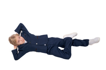 Cheerful schoolboy lies his back and rests. Boy in school uniform put his hands behind head and leg on his leg.