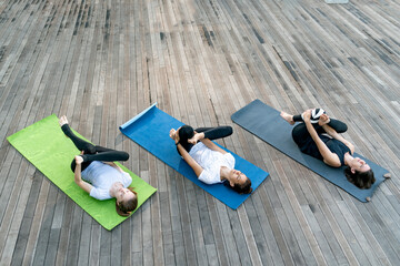 Top view of women practicing yoga outdoors on sunny day. Girls are doing stretching exercises.