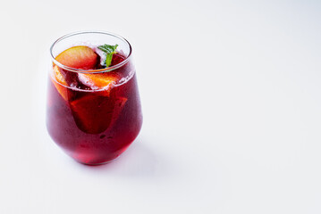 Glass with sangria, with fruits and mint. White background.