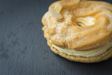 Sweet bun with cream. Fresh creamy donut on black background. Baked pastry. Sweet roll with ricotta. Delicious dessert. Homemade cuisine. Sweet food. Glazed doughnut. Bun with vanilla airy cream.