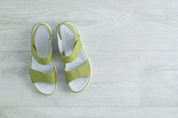 Green women's sandals on wooden white floor. View from above.