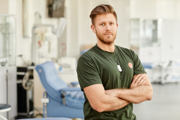 Waist up portrait of proud blood donor standing in med donation center with Save life sticker on chest and looking at camera, copy space