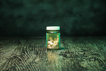 Bottle of pills on a green, grunge background. A social issues concept