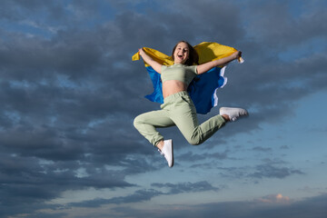 Fototapeta na wymiar happy teen girl jump with national ukrainian flag of ukraine, happiness and freedom