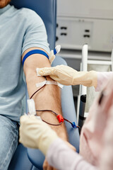 Close up of unrecognizable nurse preparing young man for blood donation or transfusion cleaning arm...
