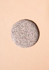 Drop of liquid coffee scrub on a beige background, top view.