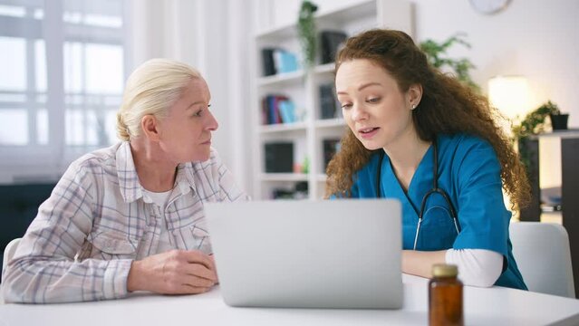 Female doctor helping senior patient to book appointment with a doctor online