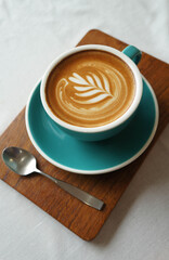 cup of coffee with a spoon  with heart shape latte art on brown old wood table at caff food and drink concept.