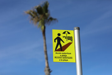the inscription allowed access to the beach on a yellow sign in Spanish and Catalan acceso autoritzat a la playa. Spanish coast