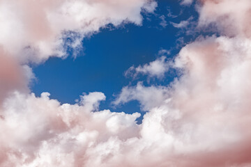 Pink fluffy cumulus clouds on a blue sky close-up.