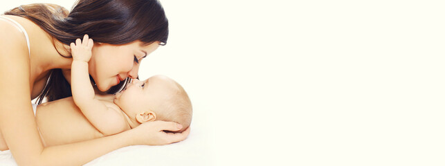 Happy mother and baby lying on the bed on white background, blank copy space for advertising text