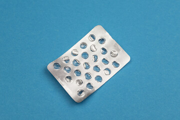 Empty used blister from tablets on a blue background, top view, flat lay.