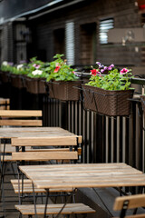 Fototapeta na wymiar empty tables in street cafe decorated with fresh potted flowers in summer city