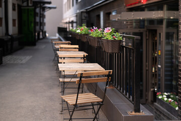 row of wooden tables in outdoor cafe on empty street