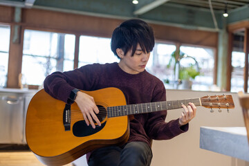 ギター演奏の練習をする20代男性