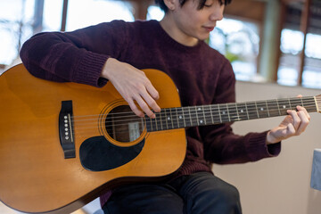 ギター演奏の練習をする20代男性