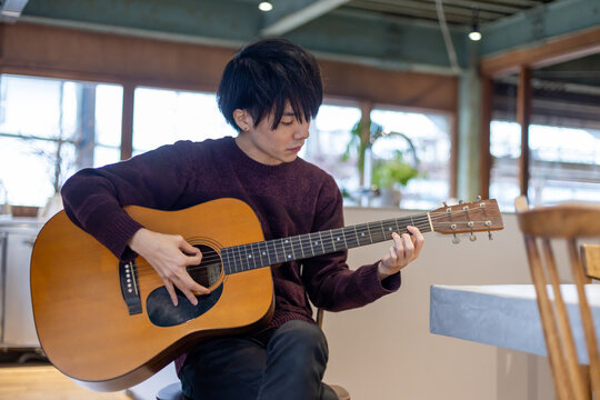 ギター演奏の練習をする20代男性