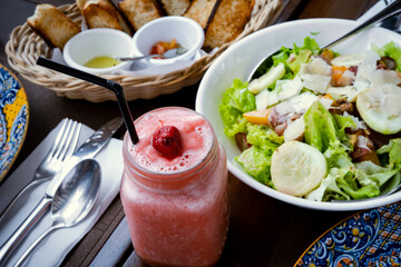 Strawberry shake, vegetable salad and bread on the table
