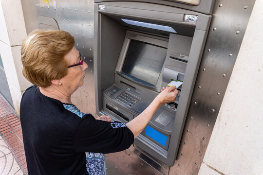 Elderly woman using an ATM in the street