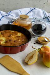 Homemade pear pie on a white table with pears in the foreground. Vertical.
