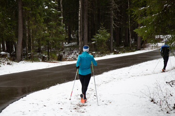 Women are engaged in Nordic walking in a winter park.