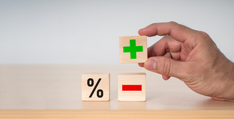 The businessman selected a wood cube with a plus symbol. The notion of interest rates in finance and mortgage rates.