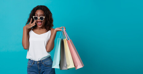 Cheerful happy teen african woman enjoying shopping, she is carrying shopping bags to get the...