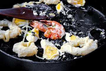 Paella negra with shrimp served in pan