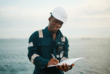 Black maritime worker filling papers in folder