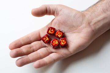 On the man's palm are five red dice with images of the symbols of the hammer and sickle. The concept of the ideology of communism.