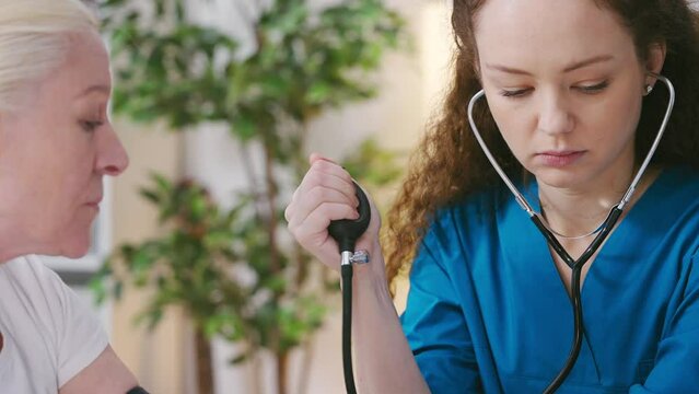 Doctor measuring senior woman's blood pressure with tonometer, health check-up