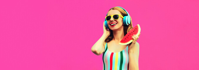 Summer colorful portrait of cheerful happy smiling young woman model posing in headphones listening to music with juicy slice of watermelon on pink background, blank copy space for advertising text