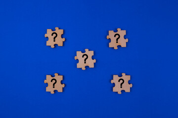 Question mark on jigsaw puzzle isolated with blue background.
