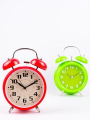 A red clock and green clock isolated with white background. Time concept. Selective focus.