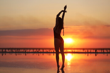 young slim beautiful woman on sunset beach, playful, dancing, running, bohemian outfit, indie style, summer vacation, sunny, having fun, positive mood, romantic, splashing water, silhouette, happy.