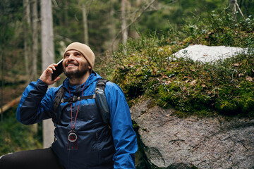 Delighted adventurer using telephone for calling to friend - obrazy, fototapety, plakaty