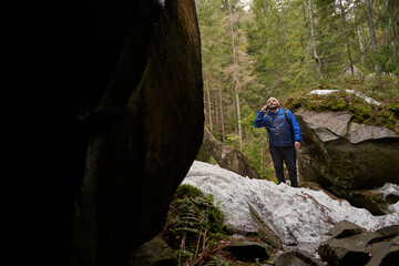 Obraz premium Active tourist standing on snowy surface near rock