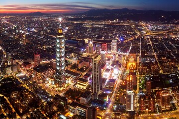 Obraz premium Aerial view of Downtown Taipei at dusk, the vibrant capital city of Taiwan, with 101 Tower standing out amid skyscrapers in Xinyi Commercial District and city lights dazzling under golden twilight sky