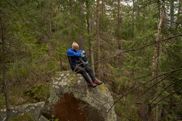Naklejka na ściany i meble Young male adventurer sitting on the rock