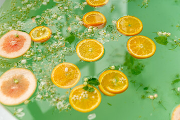 Bath filled with turquoise water with flowers and oranges.