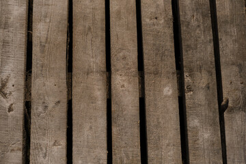 The boards are vertically parallel to each other. Raw wood for construction. Wooden pallet close-up view from above. Rural bridge or trail close-up, top view.