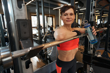 Fototapeta na wymiar Female bodybuilder with beverage in fitness studio