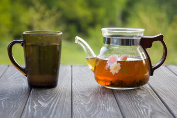 Teapot with tea in nature. Blurred background.