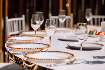 Empty glass set in restaurant. wedding, decor, celebration, holiday concept - romantic table setting with white tablecloth, plates, crystal glasses
