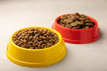 Dry food for cats and dogs in a yellow and red bowl on a gray cement background.Vitamins and nutrients for good health and pet energy.